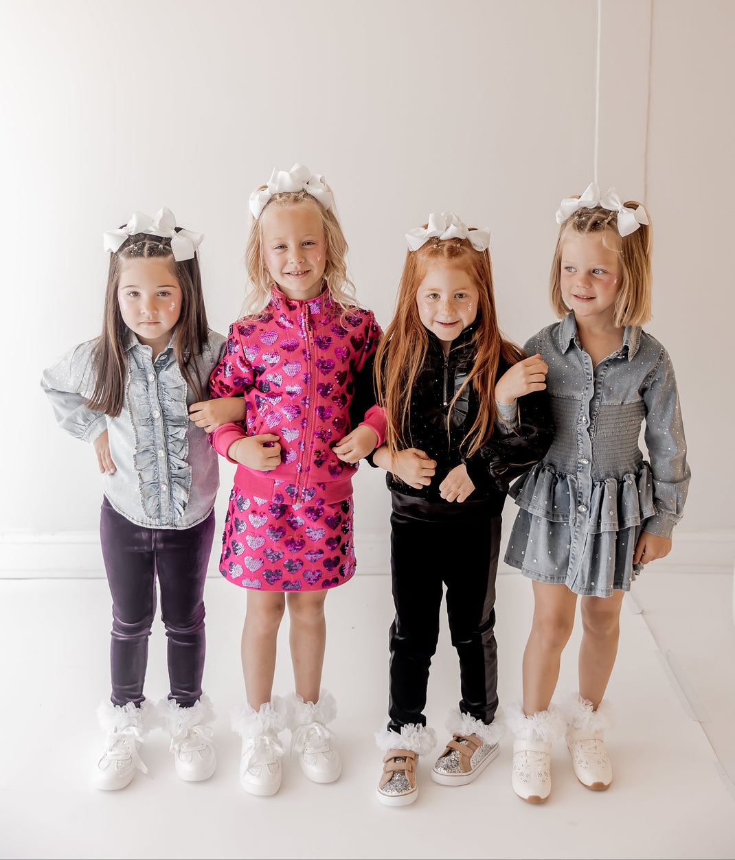 Four children standing together wearing matching outfits with decorative headbands.